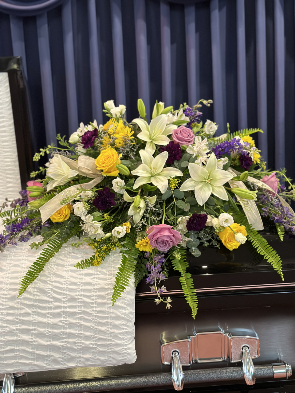 Funeral flower arrangement. Yellow and violet roses. While lilies.